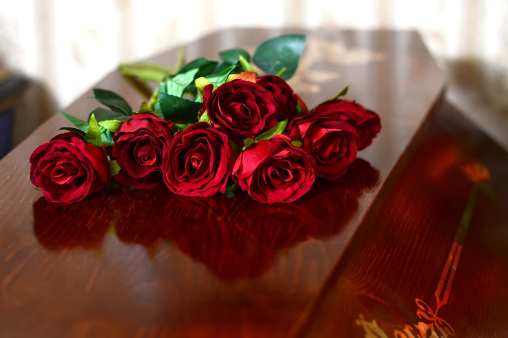 Funeral red roses lying on a casket 