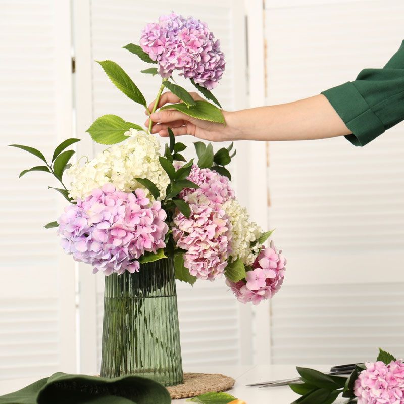 Woman arranging a vase of dusky pink and white hydrangeas