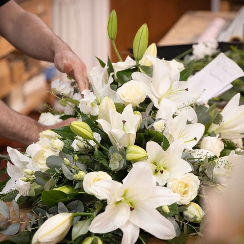 Florist preparing and sympathy flower arrangement of white lilies