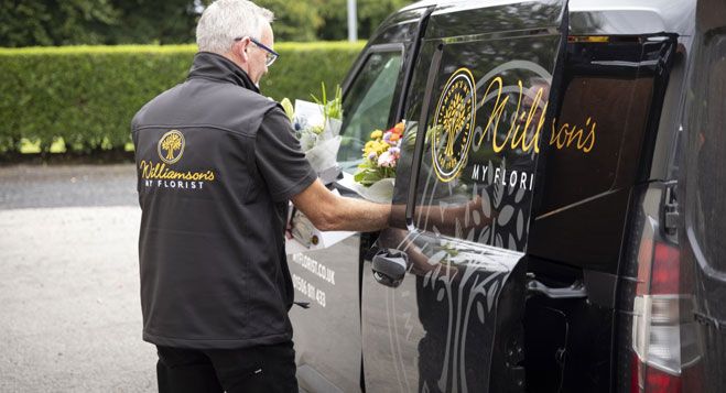 Florist from Williamson's My Florist loading fresh flower bouquets into a branded delivery van for local flower delivery in Scotland
